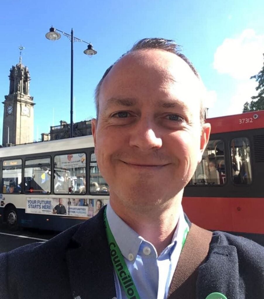 David outside the Town Hall and a bus